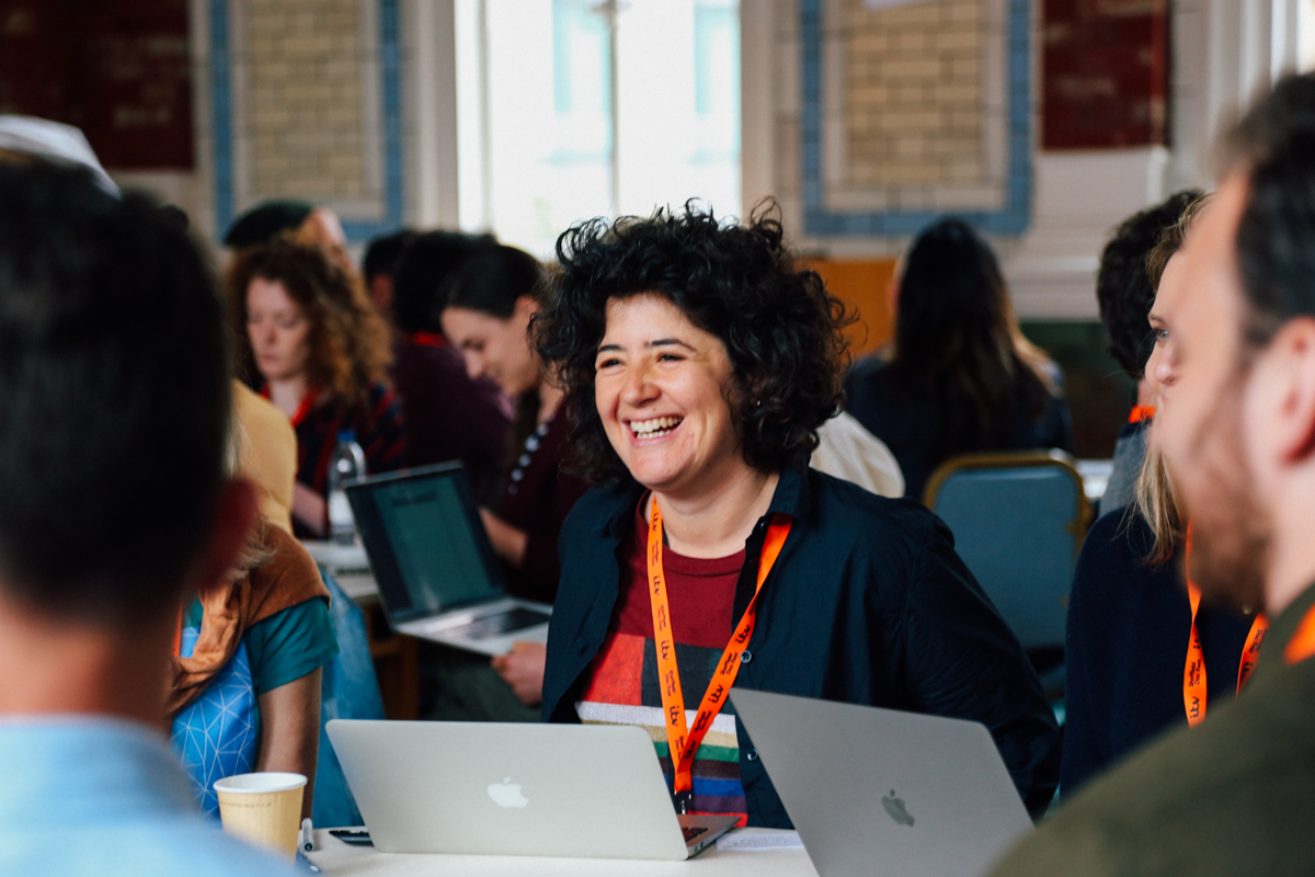 A DocFest attendee on her laptop at a table with others