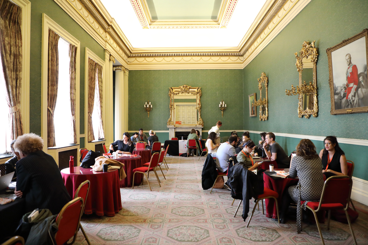 A medium sized room painted green, with red tables and chairs on the left and right
