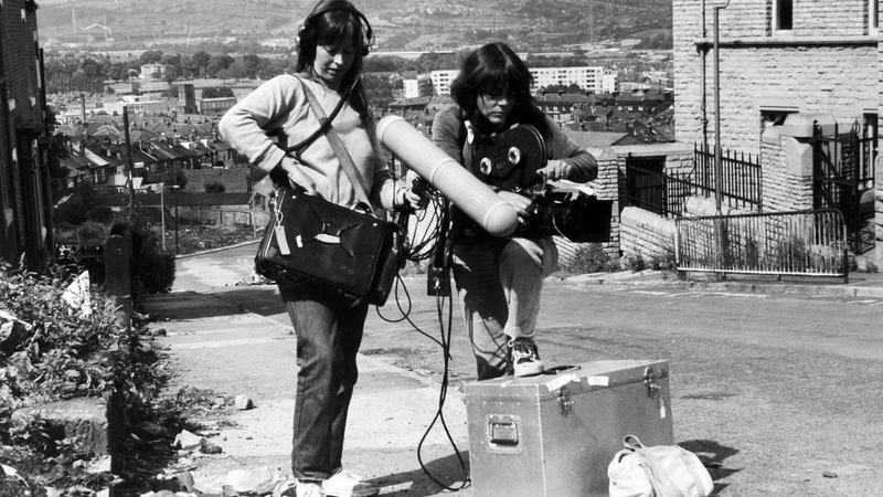 A black and white archival image of two women handling analogue filming equipment.