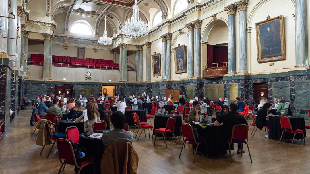 Groups of people sat at tables, in discussion, at a previous Sheffield DocFest MeetMarket in Cutler's Hall