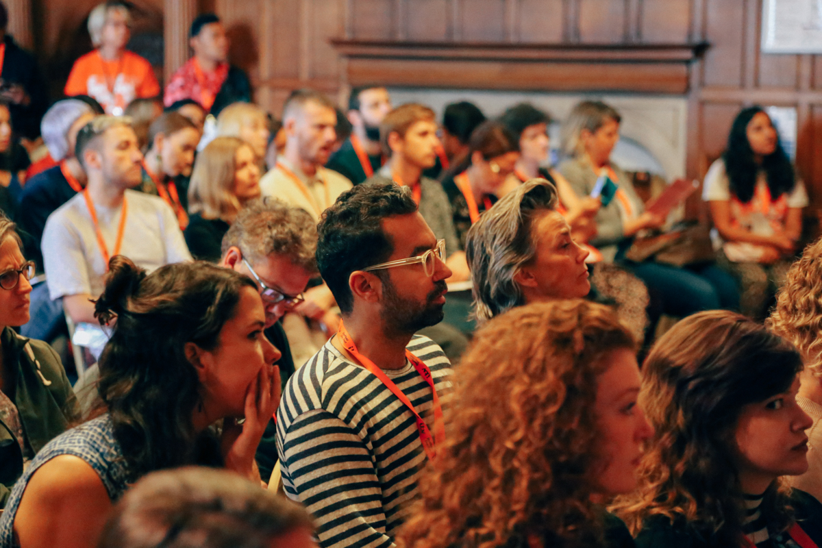 DocFest attendees sitting in rows in a medium size room listening to a talk.
