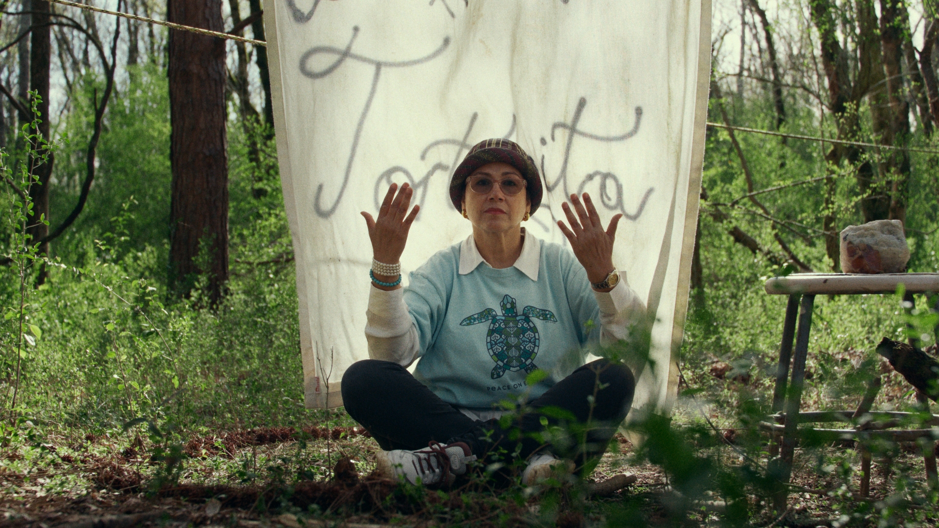 An activist sits in the forest with her hands raised