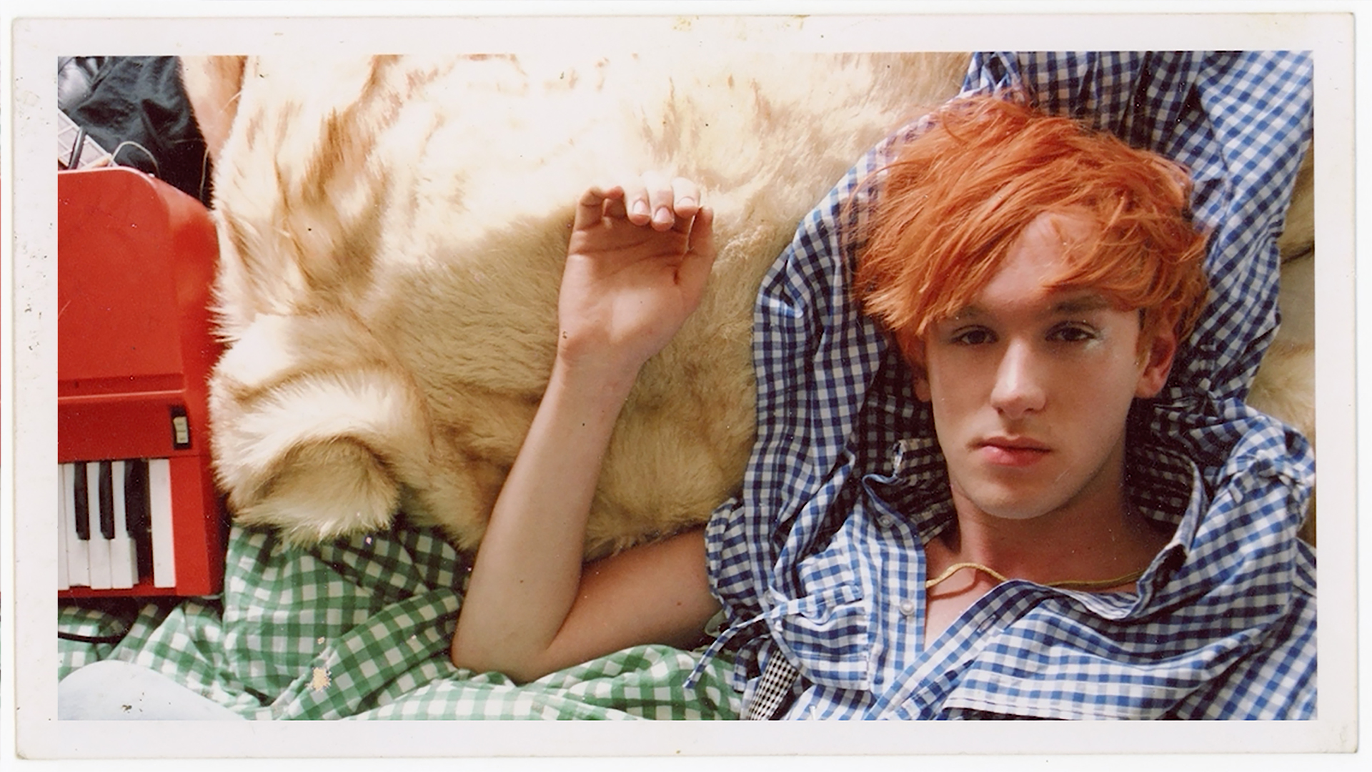 A man laying in bed next to a musical instrument. A still from the film WOLF.