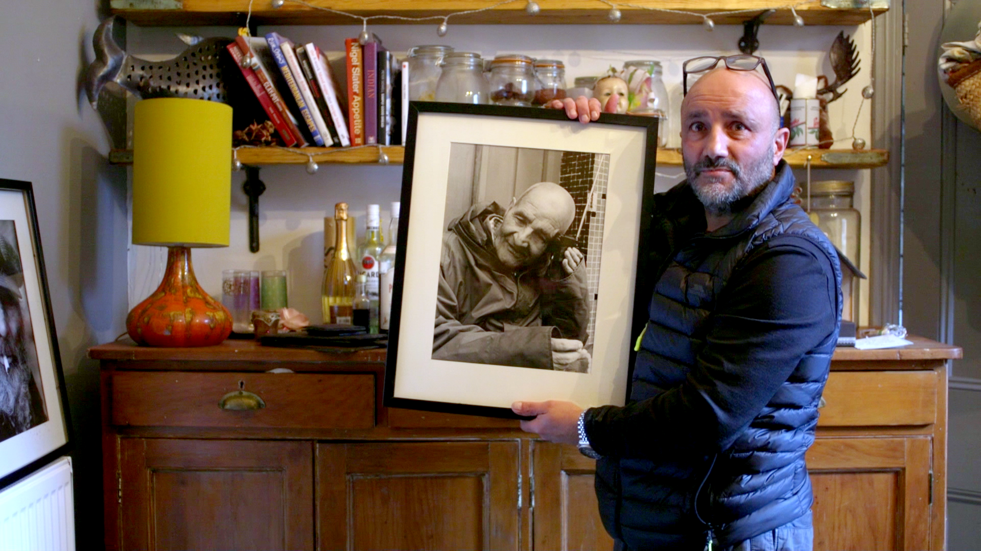 Image of a man holding a framed picture of an older man.