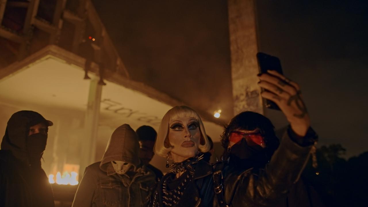 A masked group pose for a selfie outside a building at night.