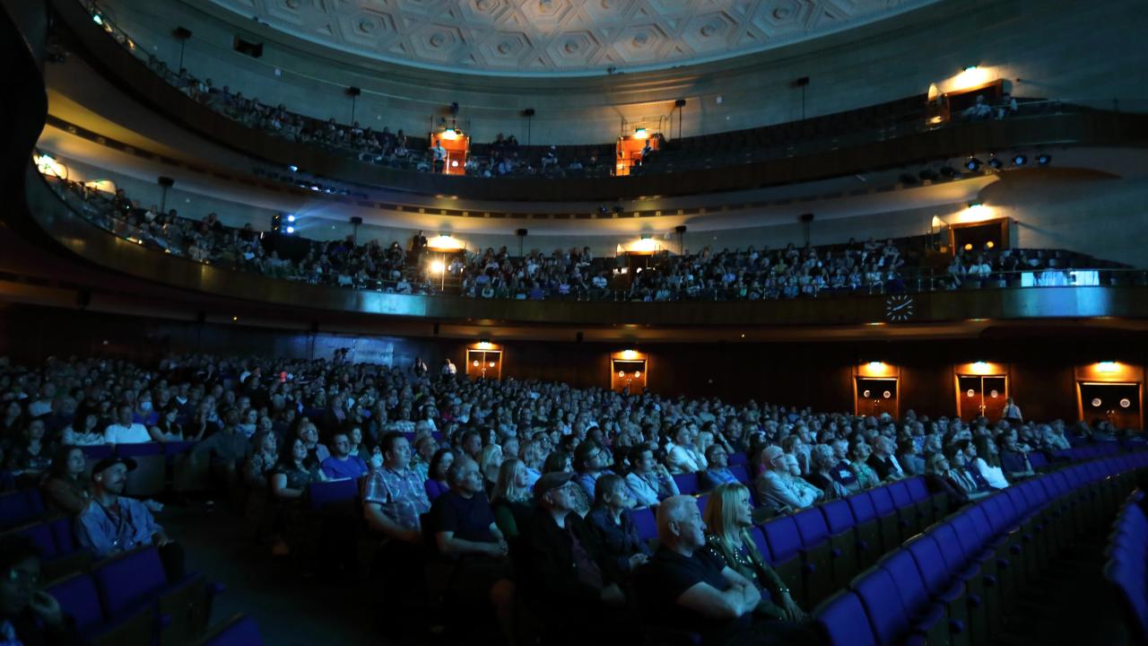 An auditorium filled with people sat down watching a film