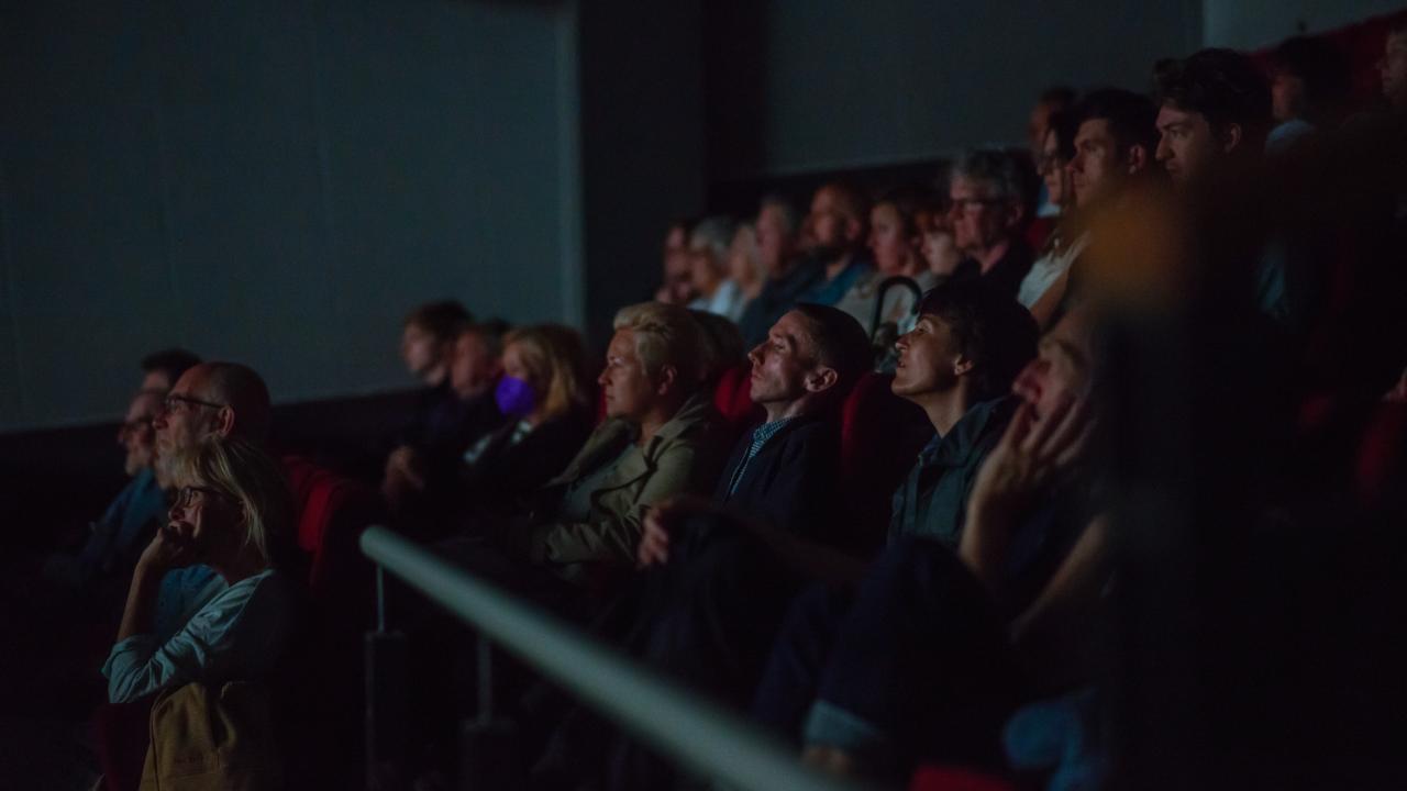 An audience sits in a dark cinema.