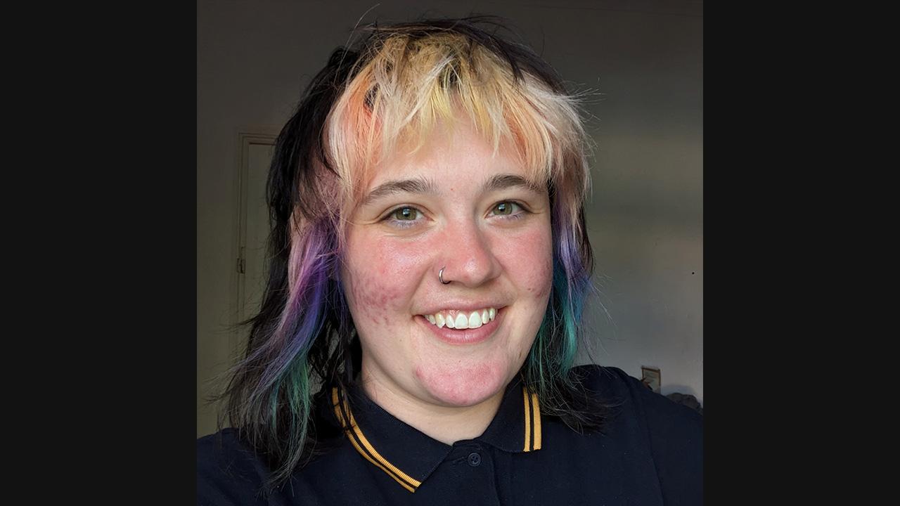 Headshot of a white woman with shoulder-length, multi-coloured hair.