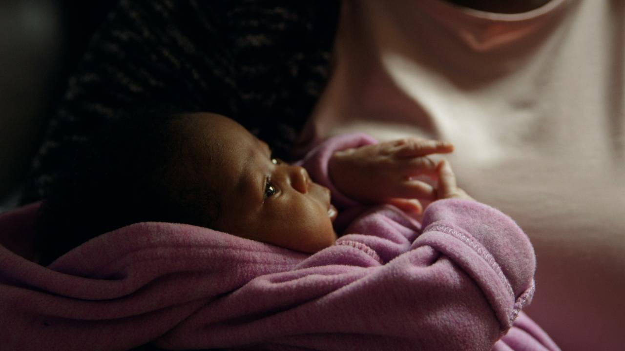 Close up image of a baby wrapped in a pink dressing gown.