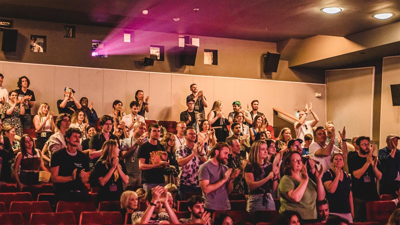 A cinema auditorium of people giving a standing ovation.