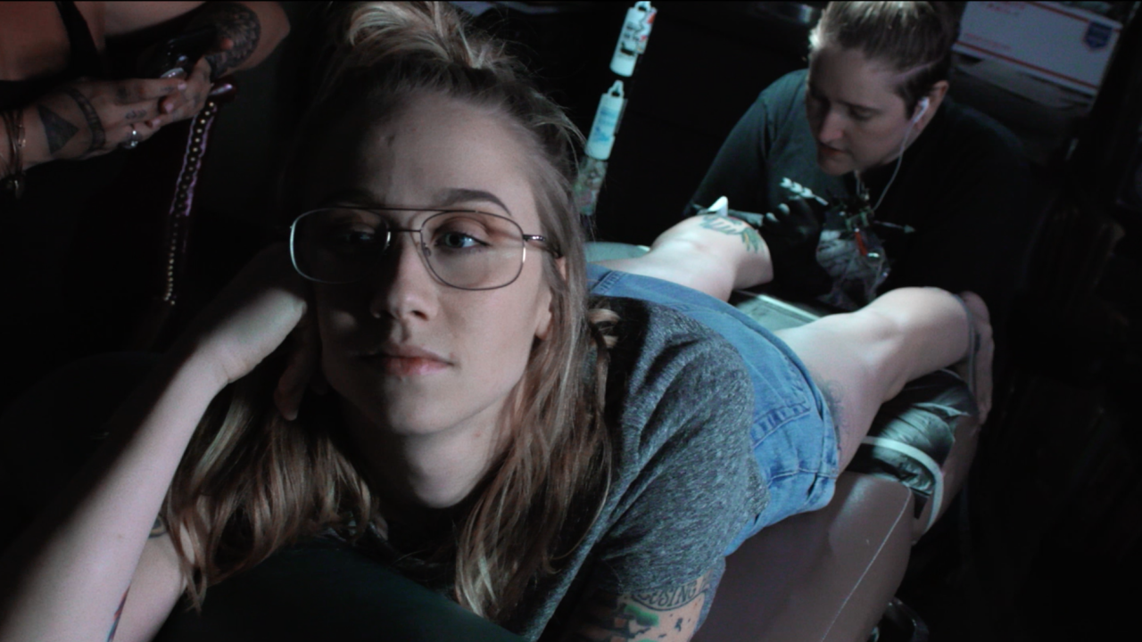 Emily Nestor lays on a tattoo bench getting her leg tattooed. 