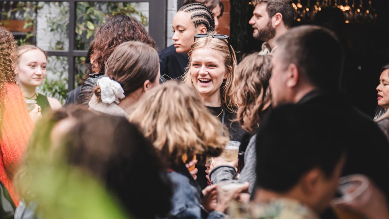 A busy crowd of people holding drinks and smiling.