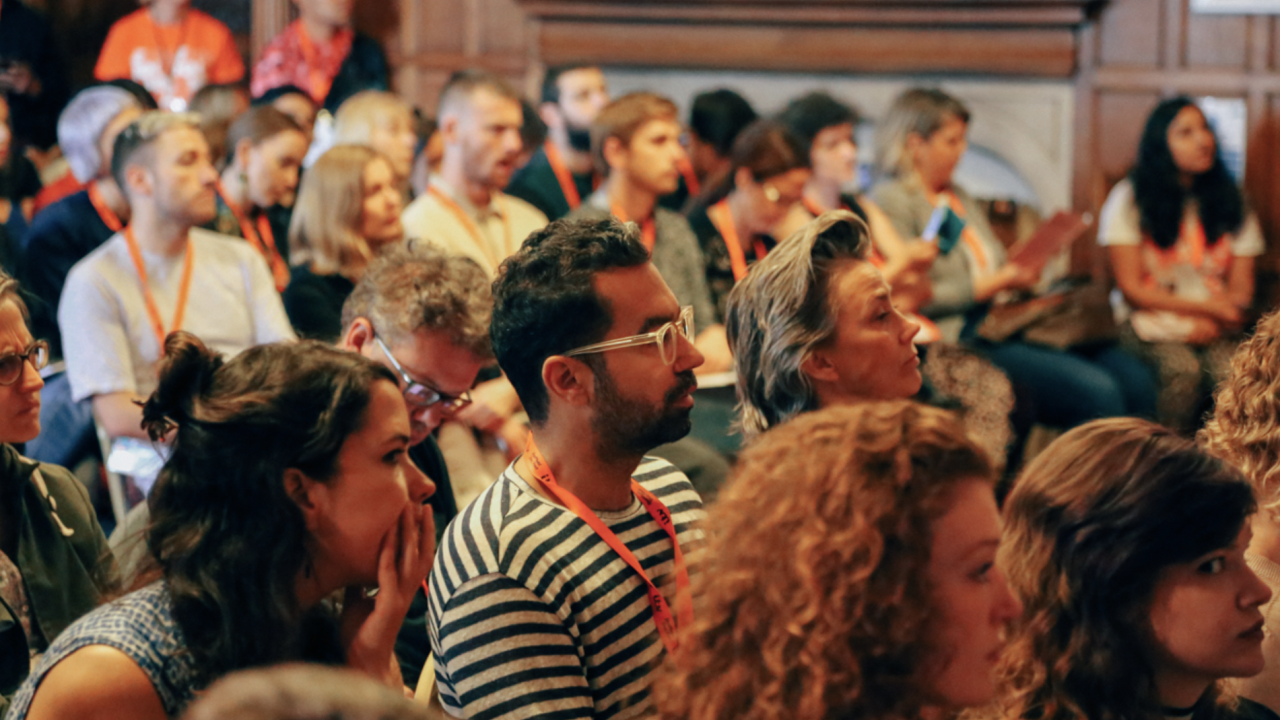 A busy crowd of people looking forward in concentration.