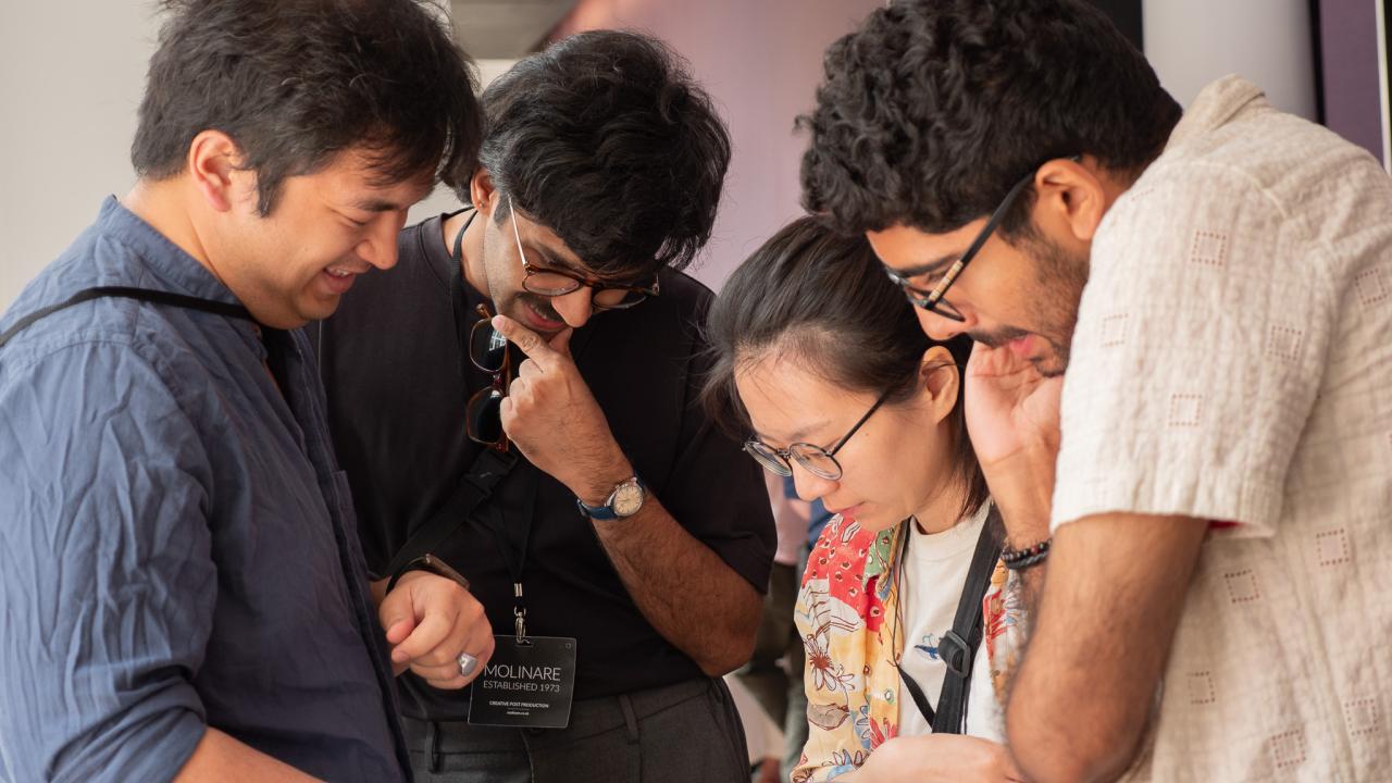 Four people huddle around a Sheffield DocFest Programme
