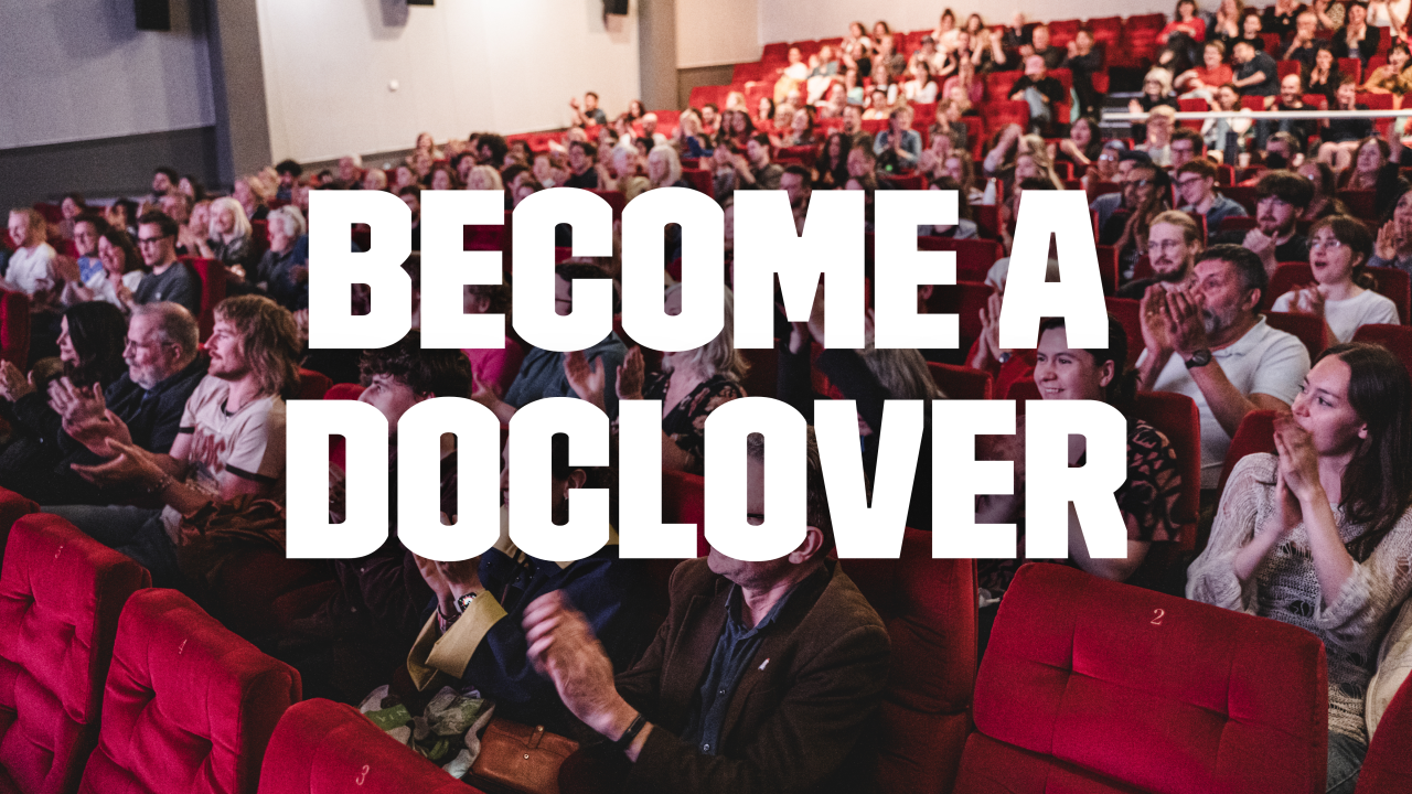 In the background image a busy cinema crowd stands to a round of applause. In large bold white text over the top of the image read 'Become a DocLover'.
