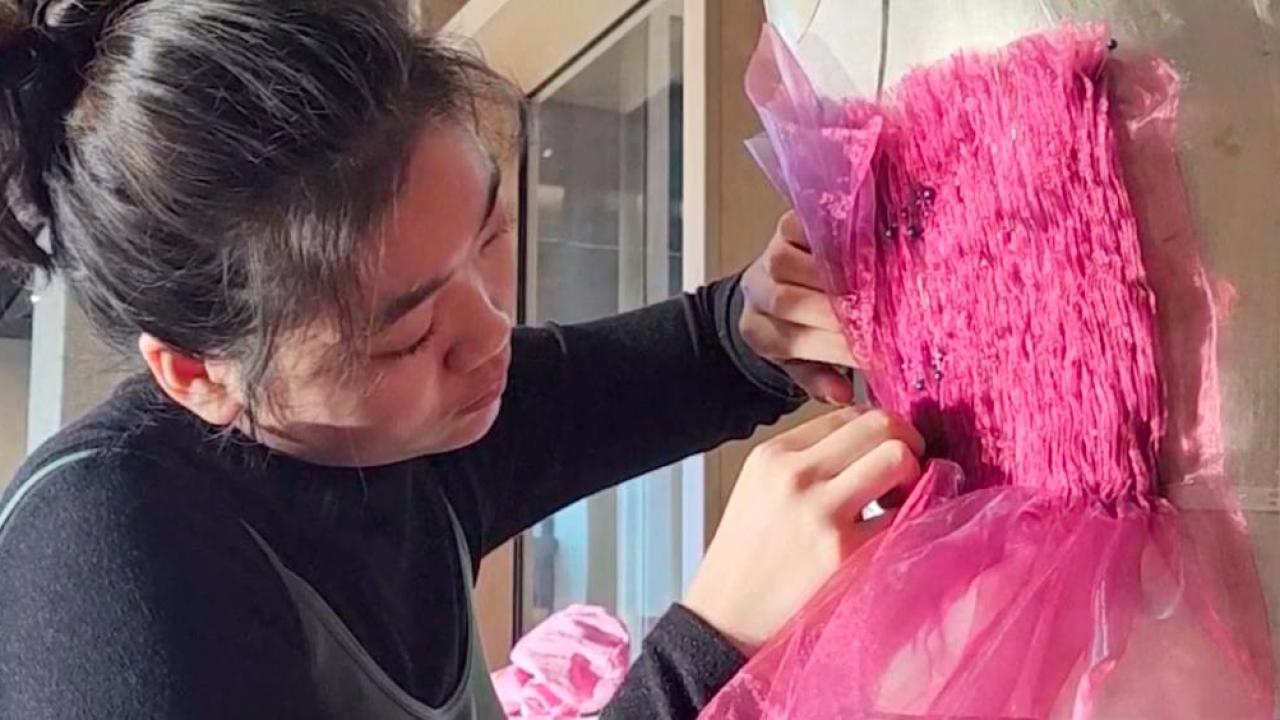 A person fixes pins on an art piece, fixing pins into a piece of bright pink material