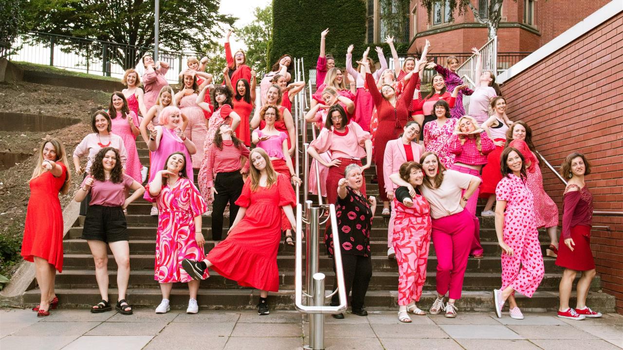 A group of people performing as a neighbourhood choir, dressed in pink.