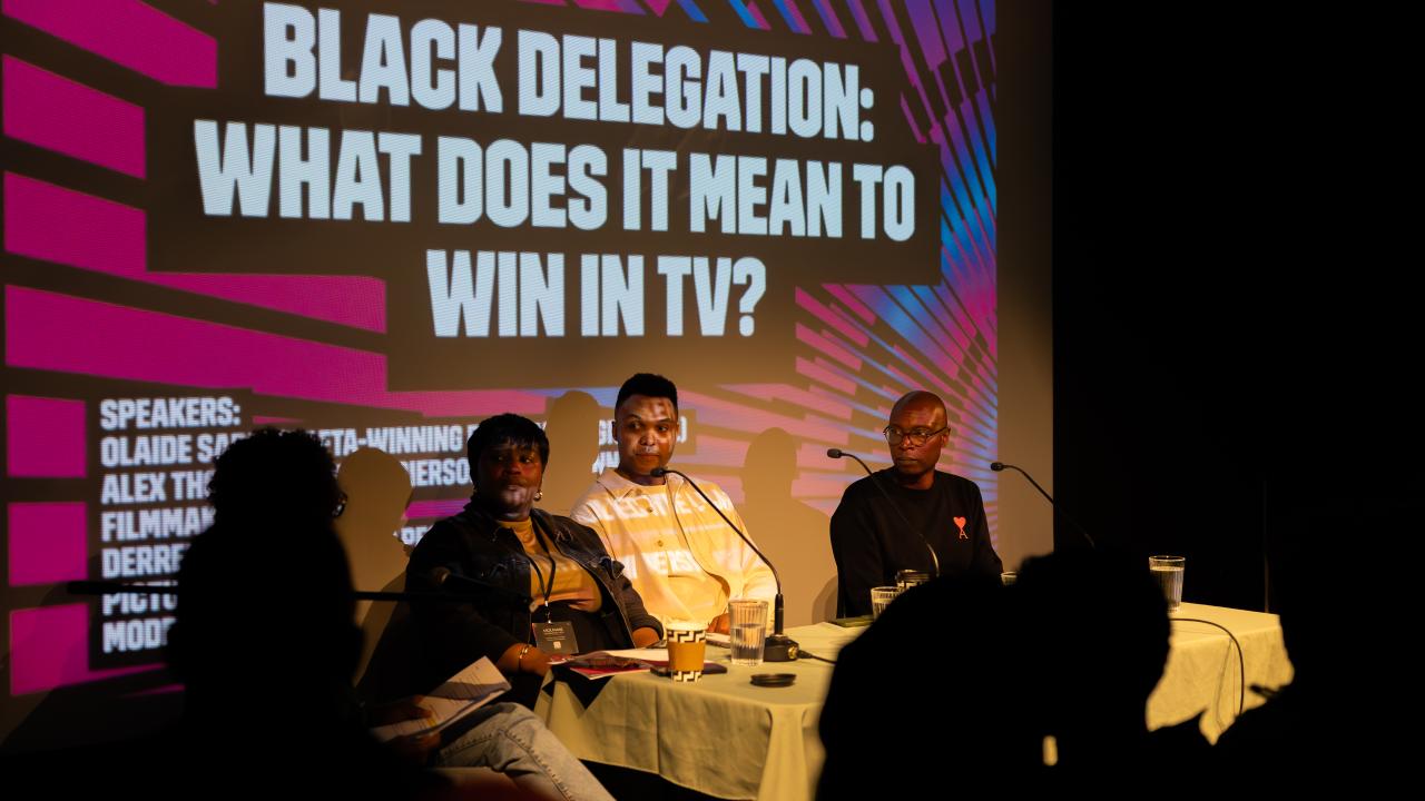 A panel of people discuss in front of a slide graphic.