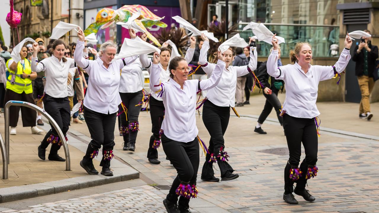 A parade of dancers make their way through Sheffield city centre.