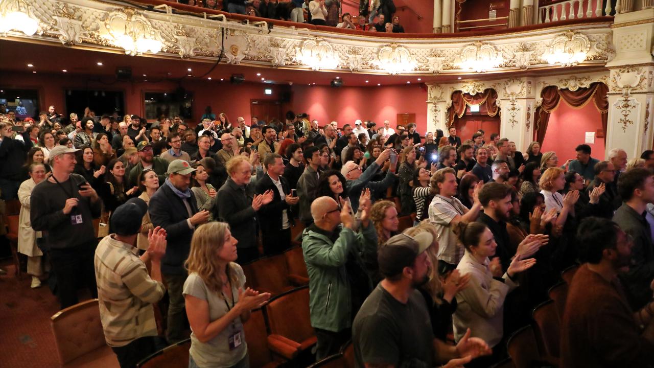 An audience stands up and claps at the end of an event.