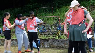 Group of four football players helping each other put their bibs on.