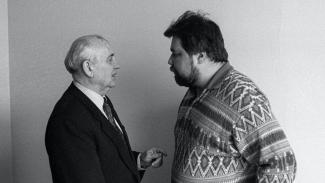 A black and white photo of two men looking at each other