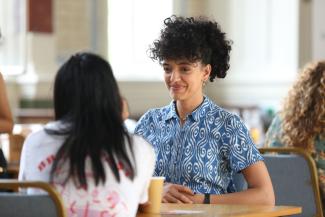 person in a blue shirt sat at a desk looking across the table at another person