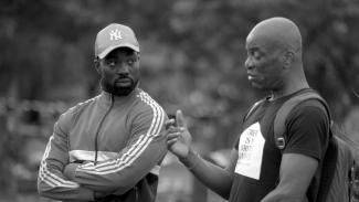 A black and white photograph of two Black men in conversation